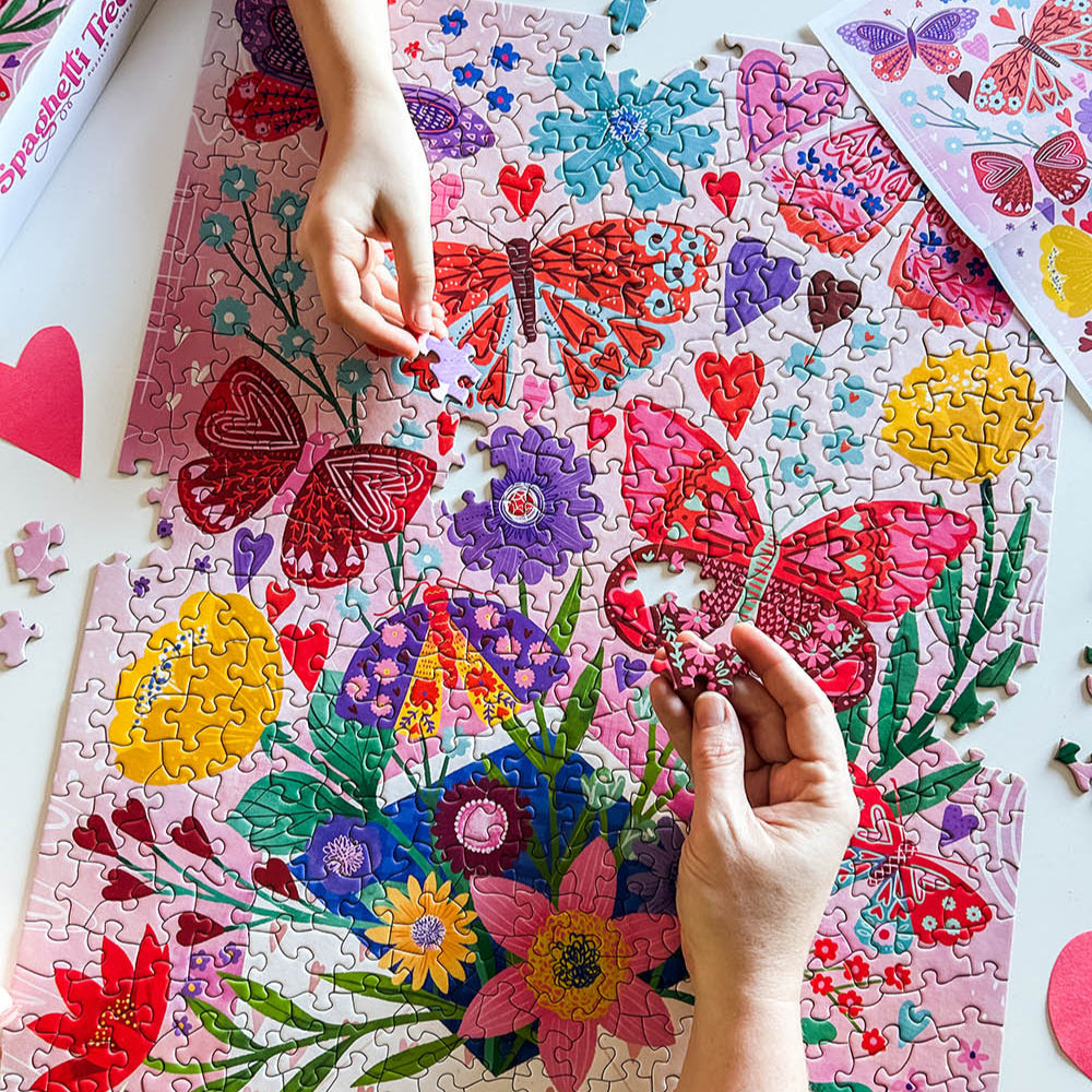 people building the "You've Got Mail" puzzle. pink puzzle featuring an envelop, flowers, and butterflies