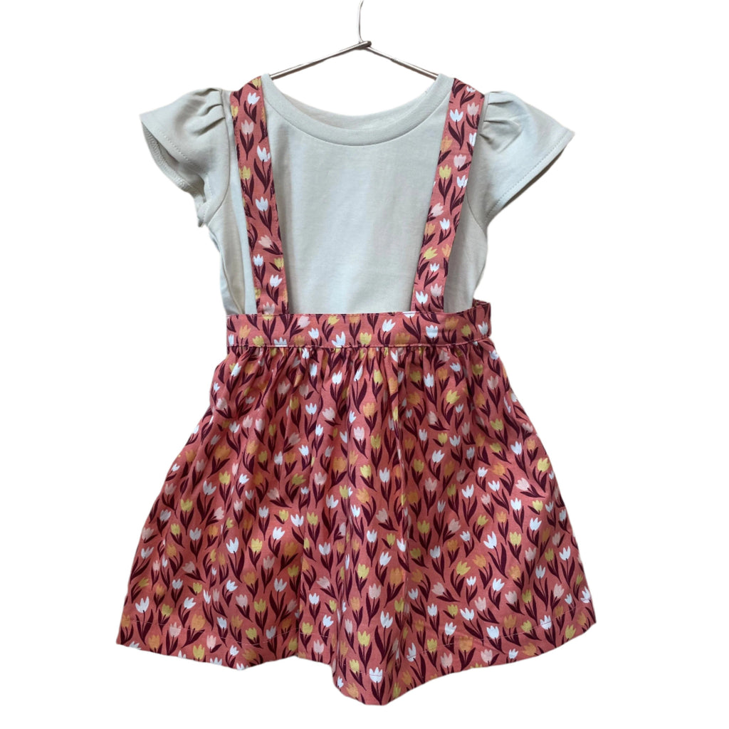 The Andi mini trouser skirt has adjustable suspenders with a button on the back. Two button holes are sewn on each suspender strap so your child can grow with their skirt making it easy to wear high on her waist when they are younger &amp; on their natural waist when older. Fabric designed by Ashley Collett for Riley Blake.