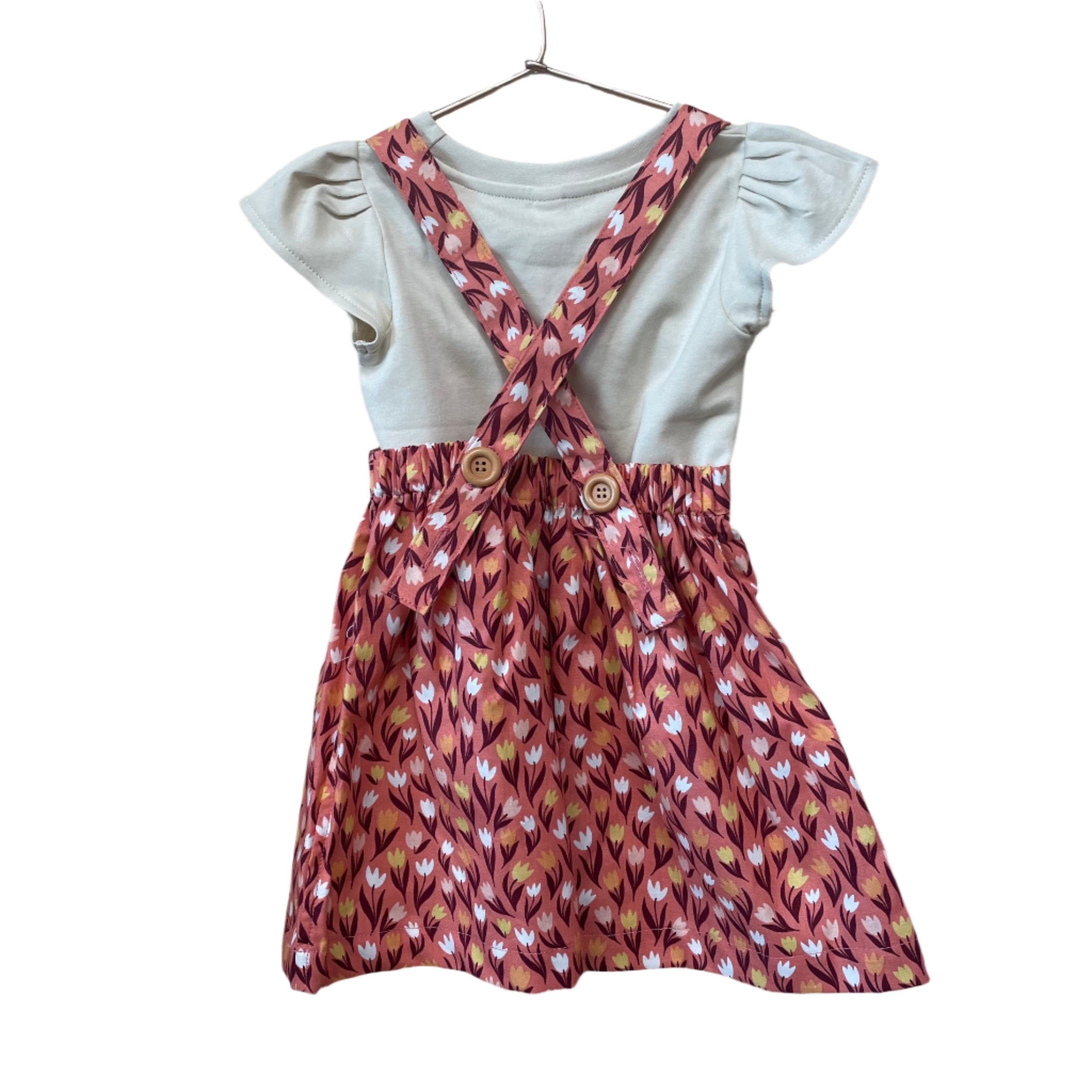 The Andi mini trouser skirt has adjustable suspenders with a button on the back. Two button holes are sewn on each suspender strap so your child can grow with their skirt making it easy to wear high on her waist when they are younger &amp; on their natural waist when older. Fabric designed by Ashley Collett for Riley Blake.