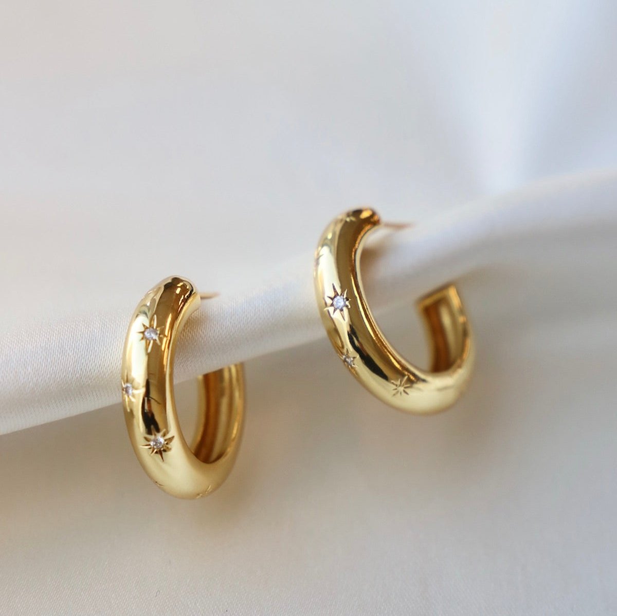A thick gold style hoop with CZ stars scattered across them. A touch of sparkle is the perfect addition to the classic gold hoop. They are a good medium size hoop that are super light on your ear.