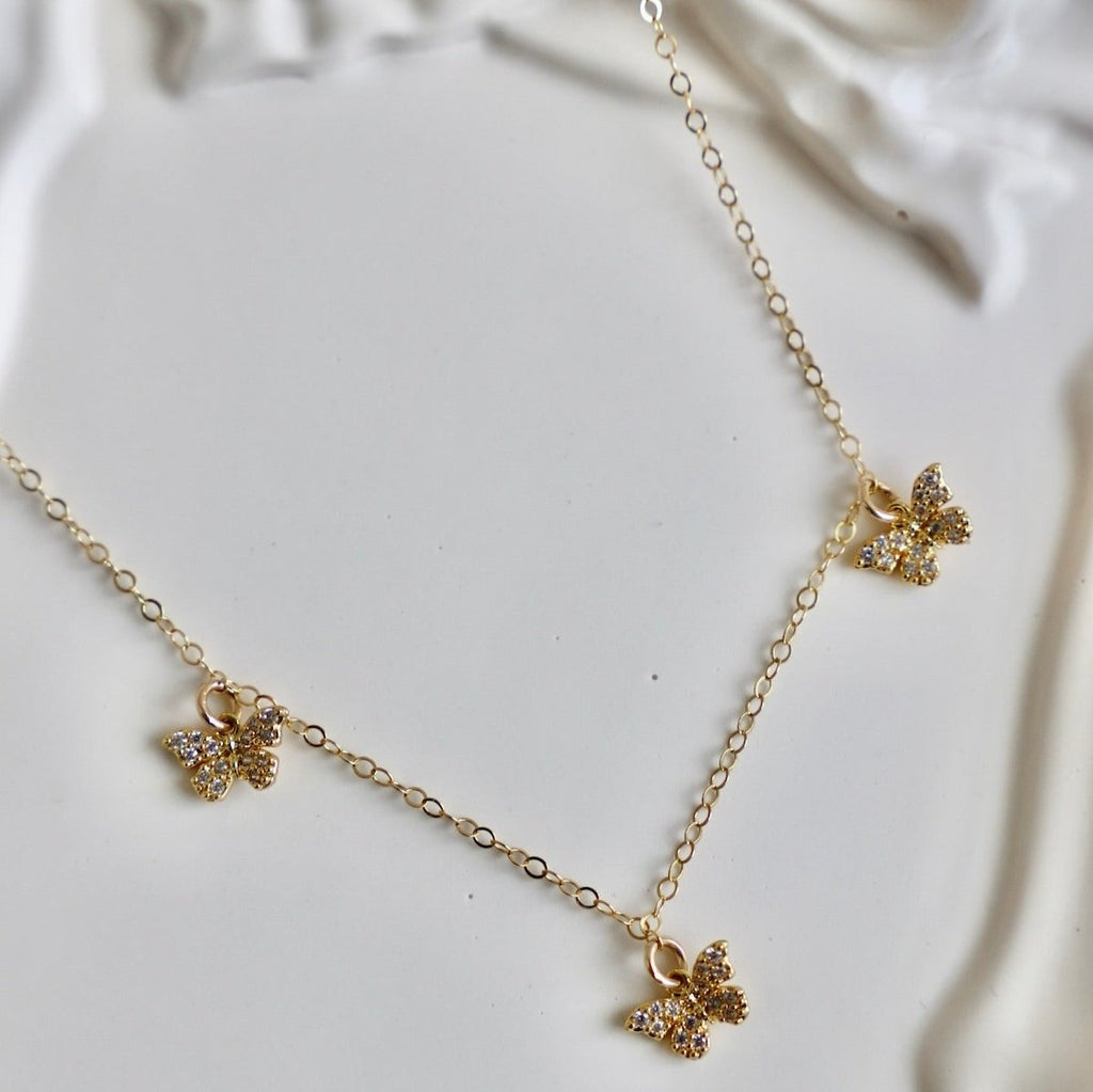 The Flutter Chain features a trio of petite butterflies gracefully fluttering on a delicate chain. With its subtle and elegant design, this necklace will add a touch of whimsy and charm to any outfit. Perfect for nature lovers and those who appreciate delicate and feminine jewelry.