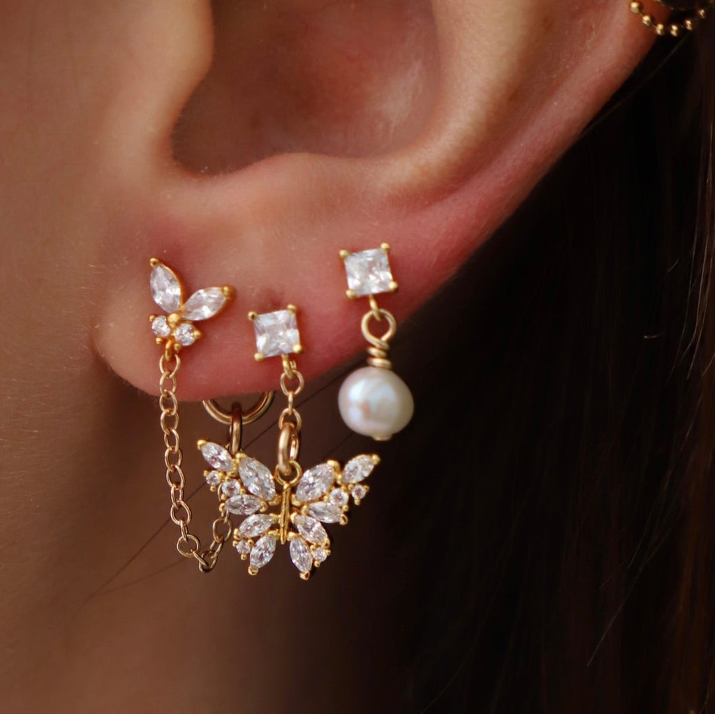 Add a touch of elegance with Claire Pearl Studs. These miniature cz square studs feature a freshwater pearl drop that will elevate any outfit. Perfect for those who love a hint of quirk and sophistication.