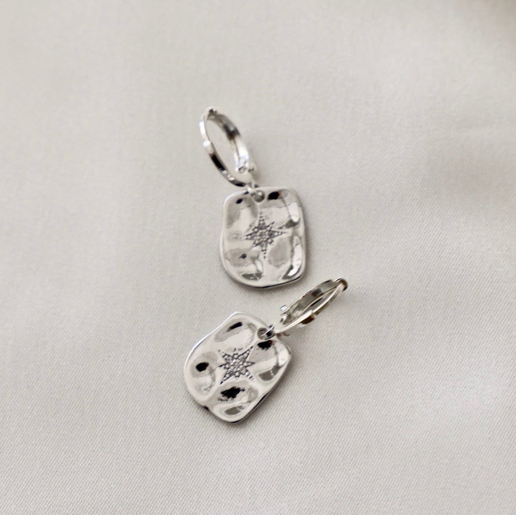 We can't get enough of our pressed styles! This silver huggies features a misshapen rectangular north star that drops down from the huggie, creating an effortless, lightweight style that you'll want to style 24/7.