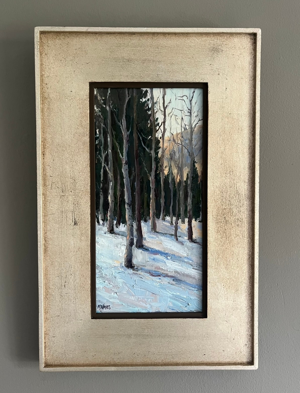Tall, barren aspens on a snowy landscape. Tall pine trees are in the background and the sky is blue with pink and blue clouds at dusk. 