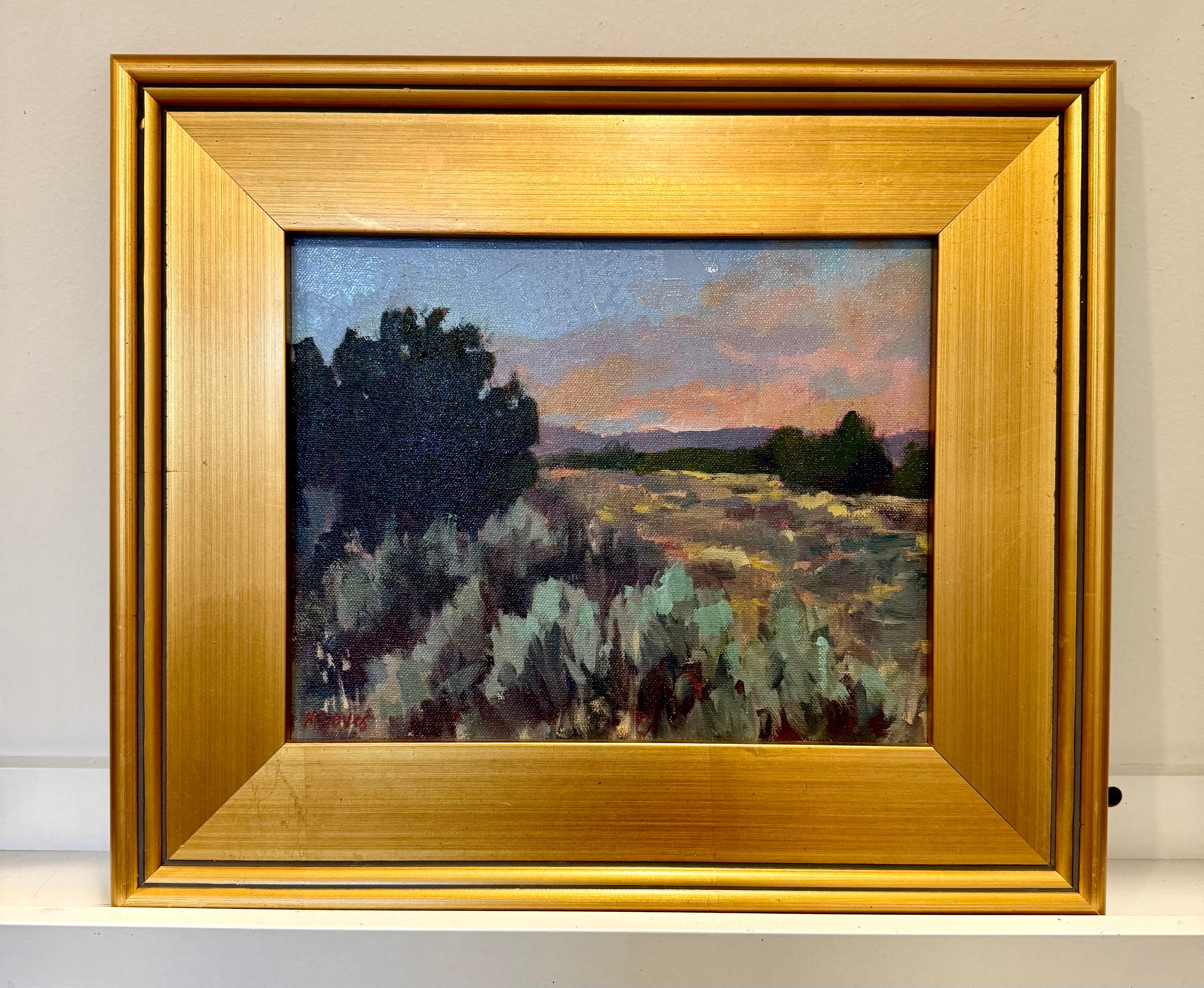 Sagebrush and golden grasses on a landscape. Green trees in the background and the sky is dusk with pink, purple, and blue hues. 
