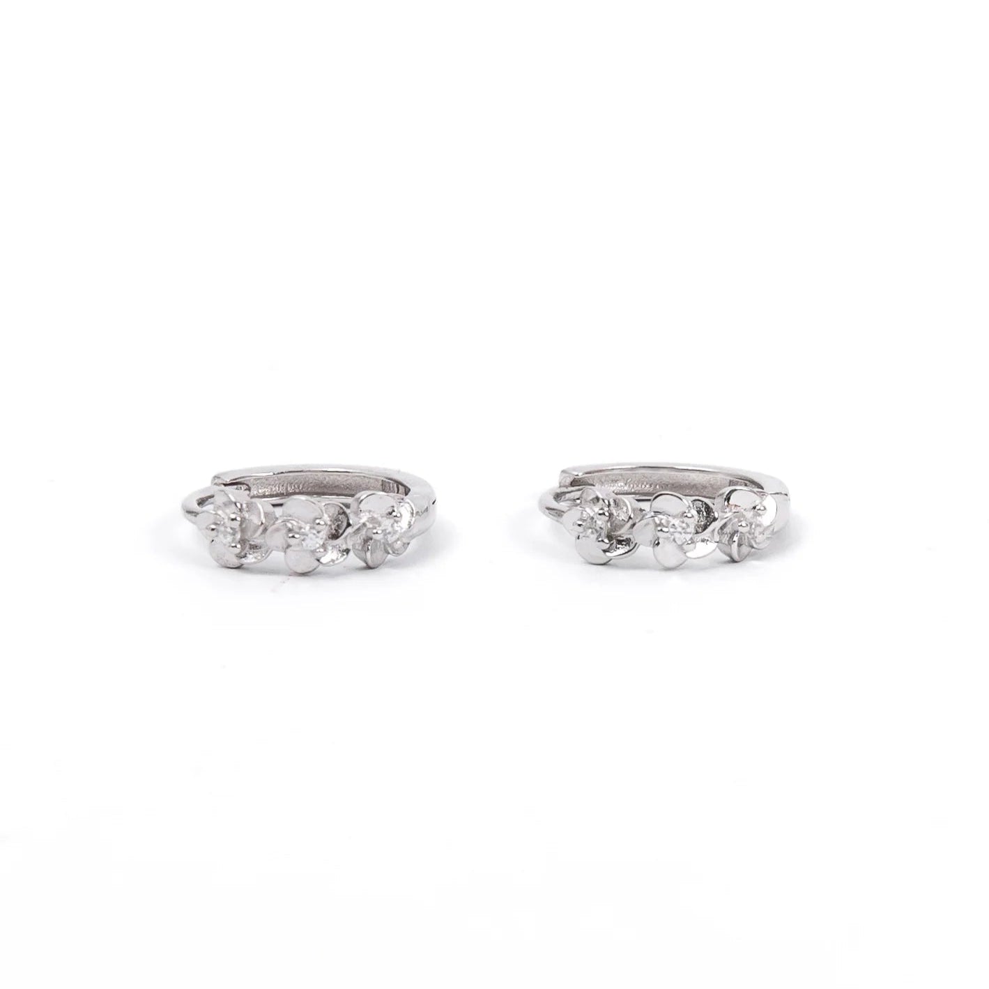 A pair of small silver hoop earrings featuring three-dimensional floral designs with tiny sparkling stones at the center of each flower. The earrings have a polished, elegant finish, combining simplicity with a delicate, nature-inspired detail