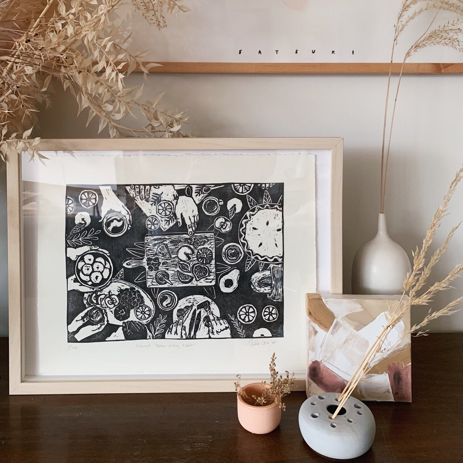 Hand carved and pressed print of a dinner table featuring a wide variety of foods in a wooden frame