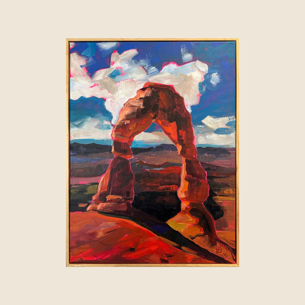 Delicate Arch with dramatic sunlight casting shadows in to the foreground.  Blue skies with white fluffly clouds.  Mountain vistsas in the back ground.