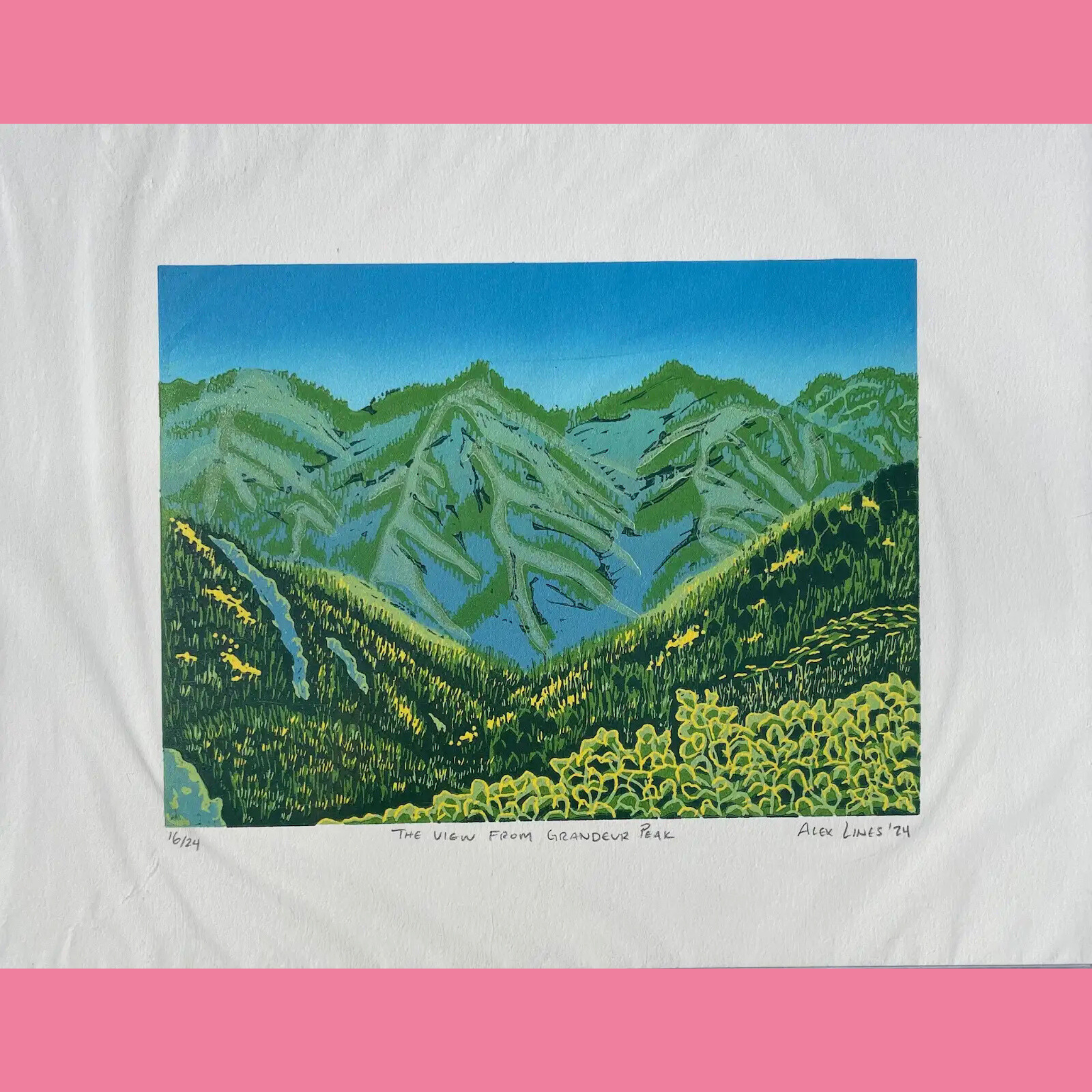 A vibrant multi-color linocut print captures a panoramic mountain view from Grandeur Peak, featuring layered green forested ridges and slopes in the foreground with patches of yellow wildflowers, rising to jagged blue-green peaks under a clear sky fading from deep blue at the top to lighter near the horizon. The artwork is printed on white paper with the edition number "16/24," the title "THE VIEW FROM GRANDEUR PEAK," and the signature "Alex Lines '24" handwritten below, surrounded by a bright pink border.