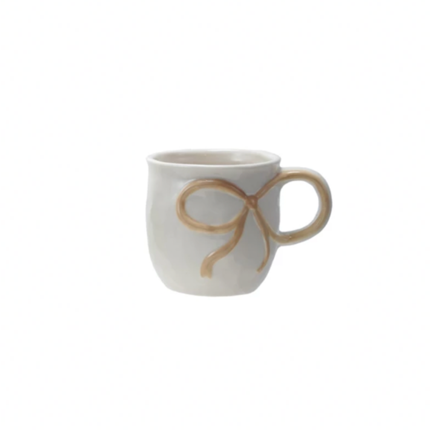 White mug with a gold bow design on a white background
