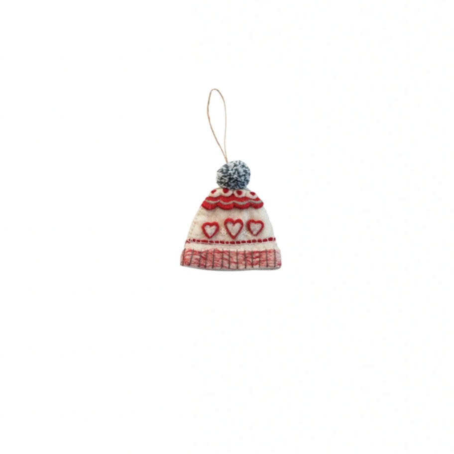 Small knitted hat ornament with heart patterns on a white background