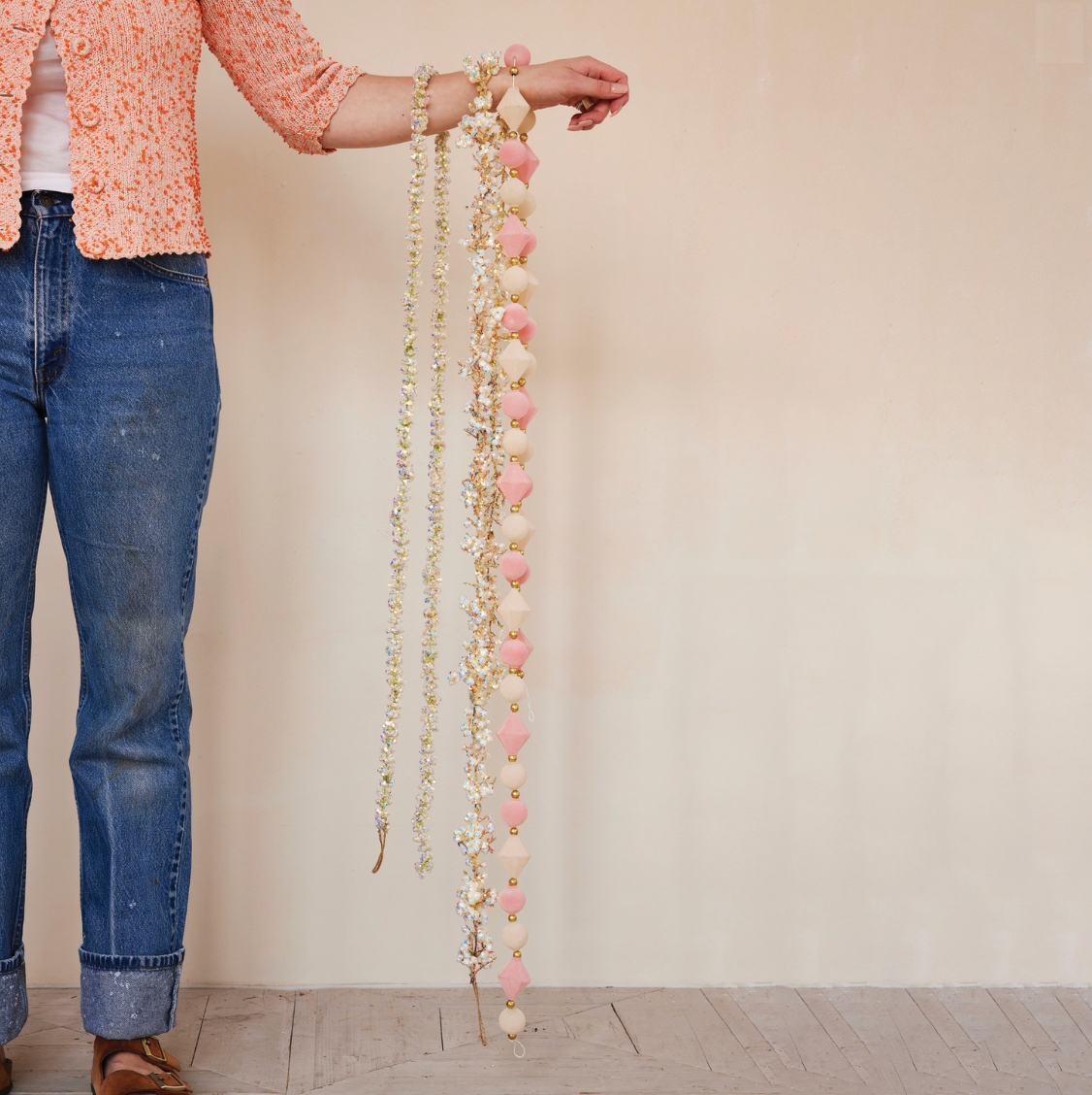Person holding two long decorative garlands against a plain background