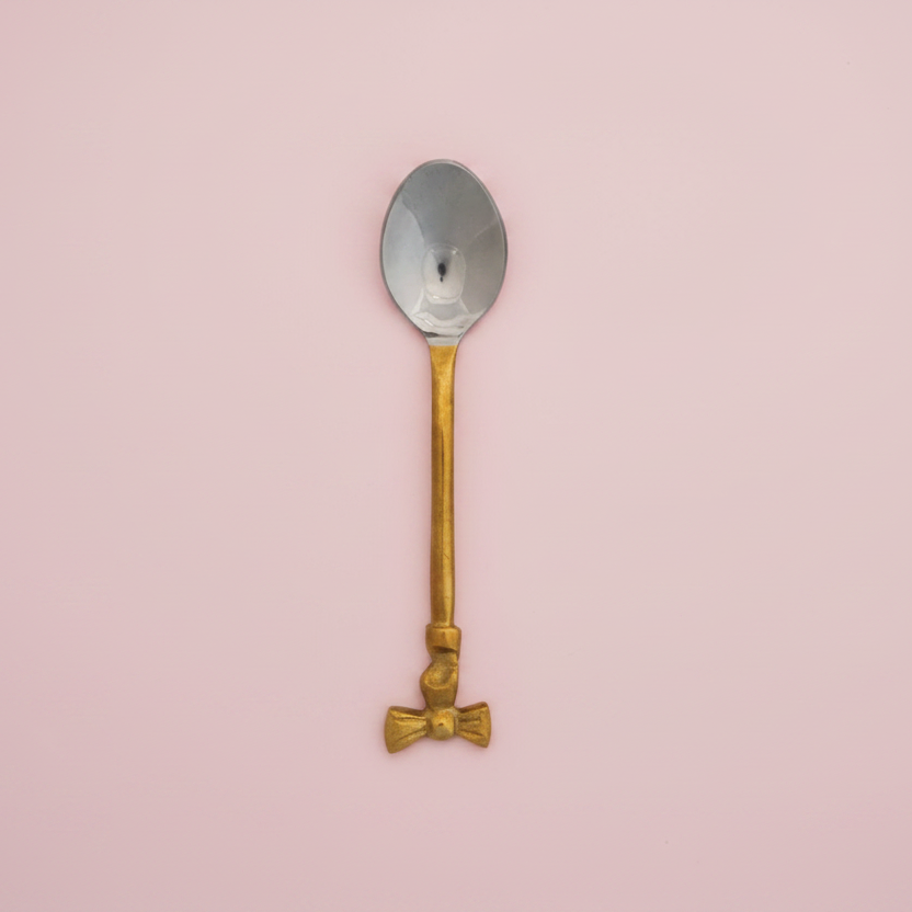 Spoon with gold handle & bow on top of handle on a white background