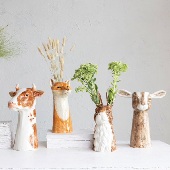 Four animal-themed vases with plants on a white surface and light gray background