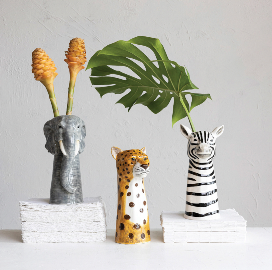 Three animal-themed vases with plants on a neutral background