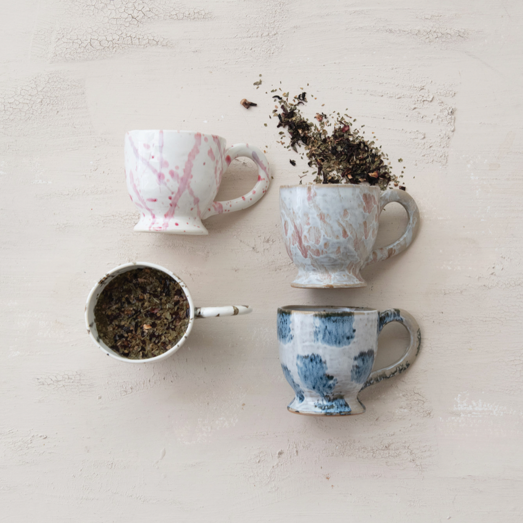 Four ceramic cups with different patterns on a textured surface
