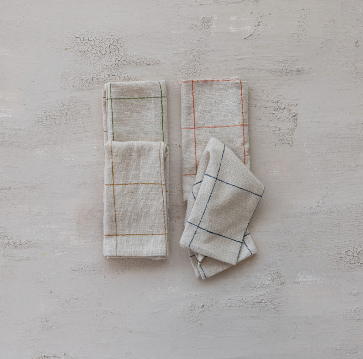 Set of three folded grid towels on a textured light gray surface