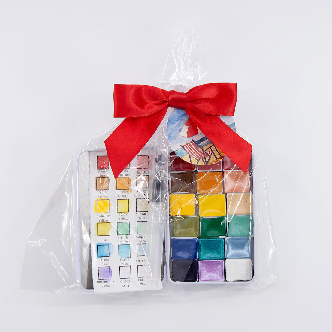 Set of watercolor pans in a clear bag with a red bow on a white background