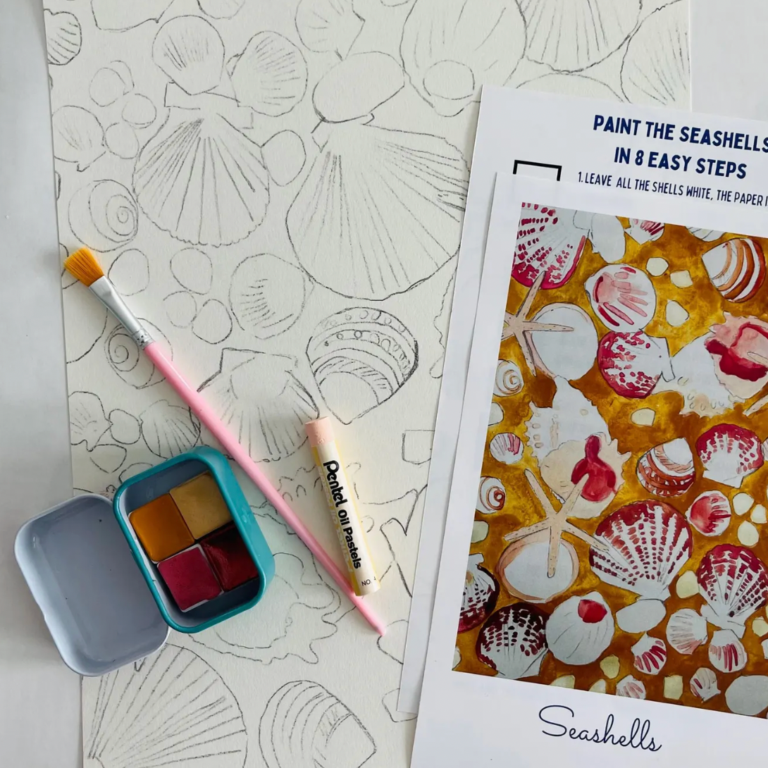 Coloring book with seashell design, paint palette, and brush on a white surface.