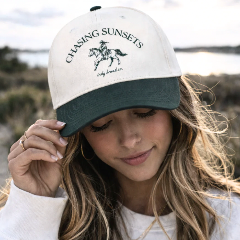 The Chasing Sunsets Hat is a vintage-inspired snapback featuring a hand-drawn western rider and horse, finished with classic arched lettering