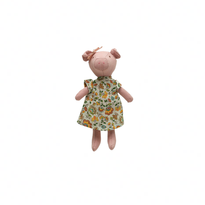 Stuffed animal pig toy with a floral dress on a white background