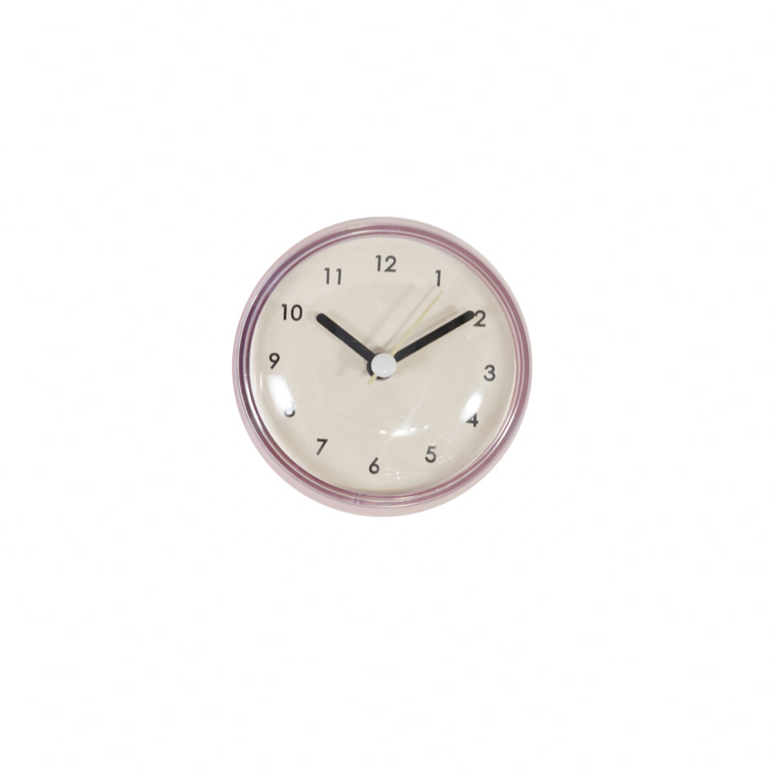 Small Pink Round wall clock with black hands on a white background. 