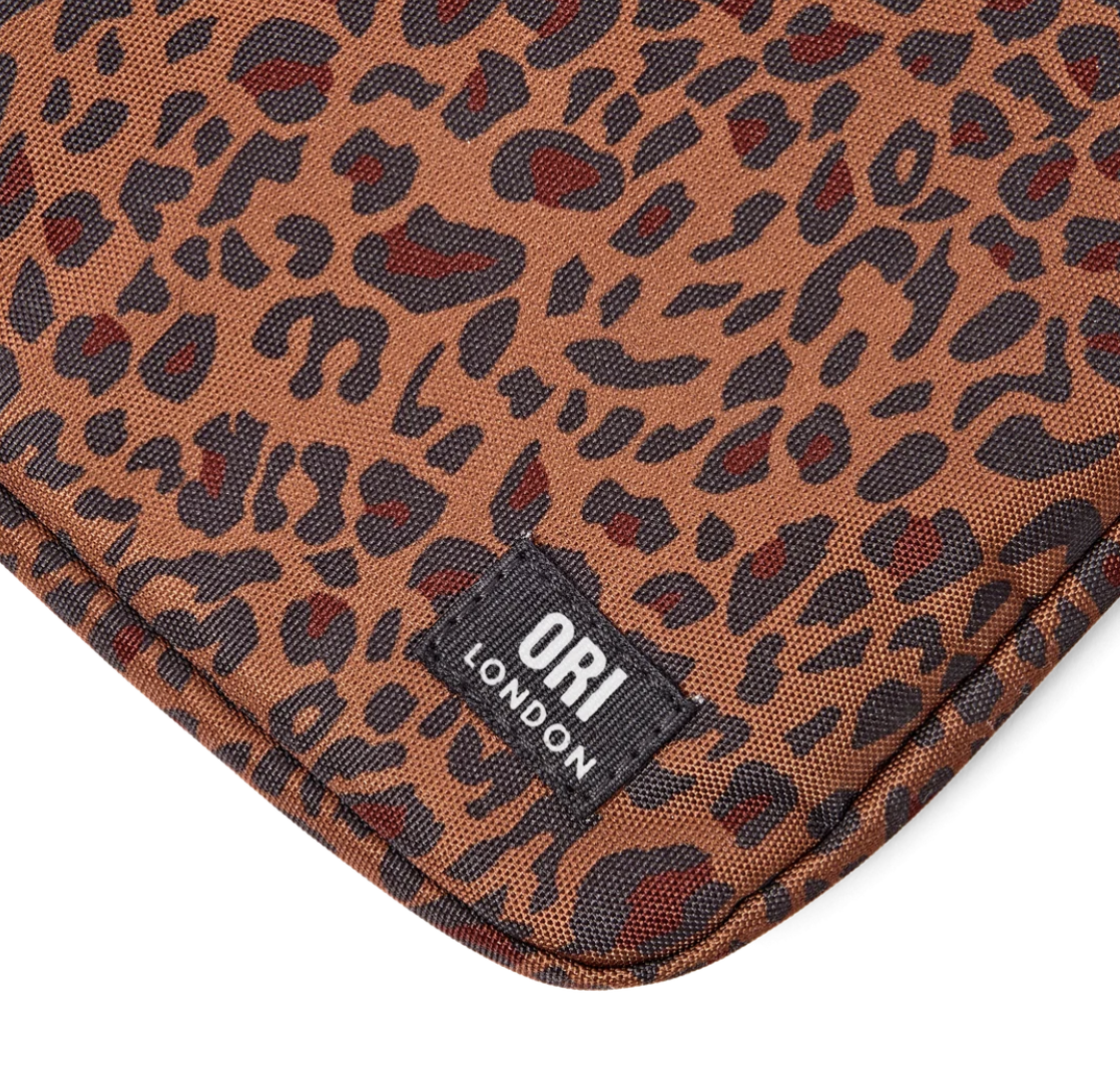 Close-up of a leopard print textile product corner with a black brand patch reading ORI LONDON, on a white background.
