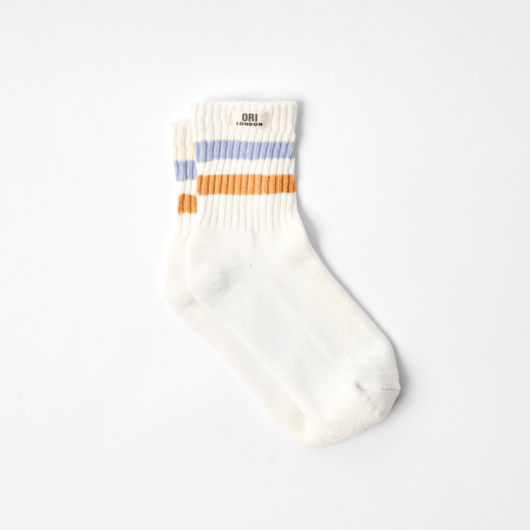 A pair of off-white crew socks with horizontal stripes in light blue and orange near the ribbed cuff, displayed on a clean white background.