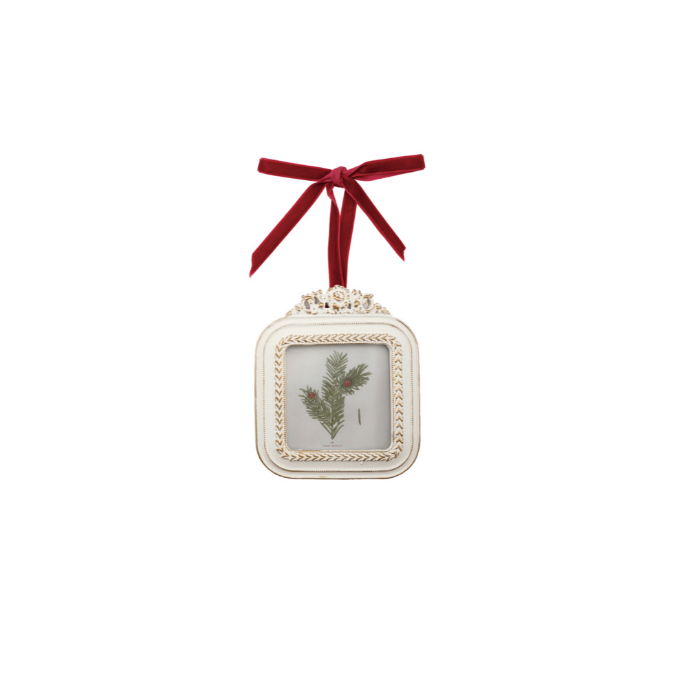 A square vintage-style Christmas ornament with an ornate cream-colored frame, featuring a central botanical illustration of holly leaves, suspended by a red ribbon bow against a plain white background. Holds 3" x 3" Photo