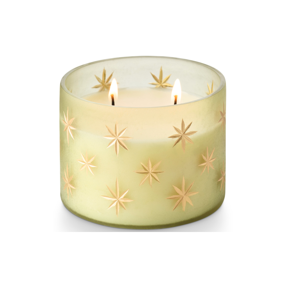 A frosted glass candle holder with a pale yellow-green tint and embossed star patterns, containing white wax, set against a plain white background.