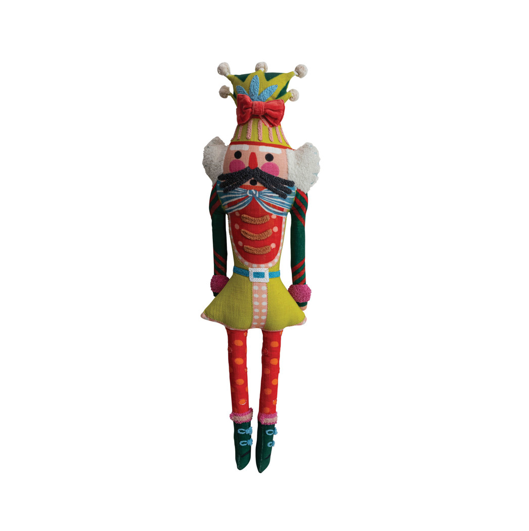 A colorful handmade fabric nutcracker doll with a striped jester hat, red and yellow outfit, white ruffles, and a large black mustache, isolated on a white background.