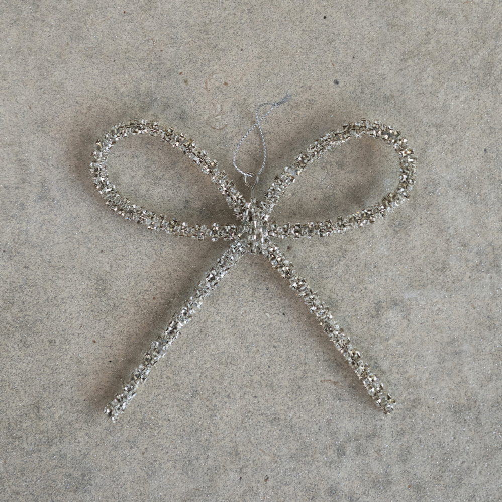 Add a touch of elegance to your décor with this Metal Silver Rhinestone Bow Ornament. Crafted from durable metal and adorned with sparkling rhinestones, this charming bow captures light beautifully, enhancing any space with subtle shimmer. Its refined design makes it a perfect accent for holiday decorating or everyday sophistication, adding a graceful sparkle wherever it is displayed.