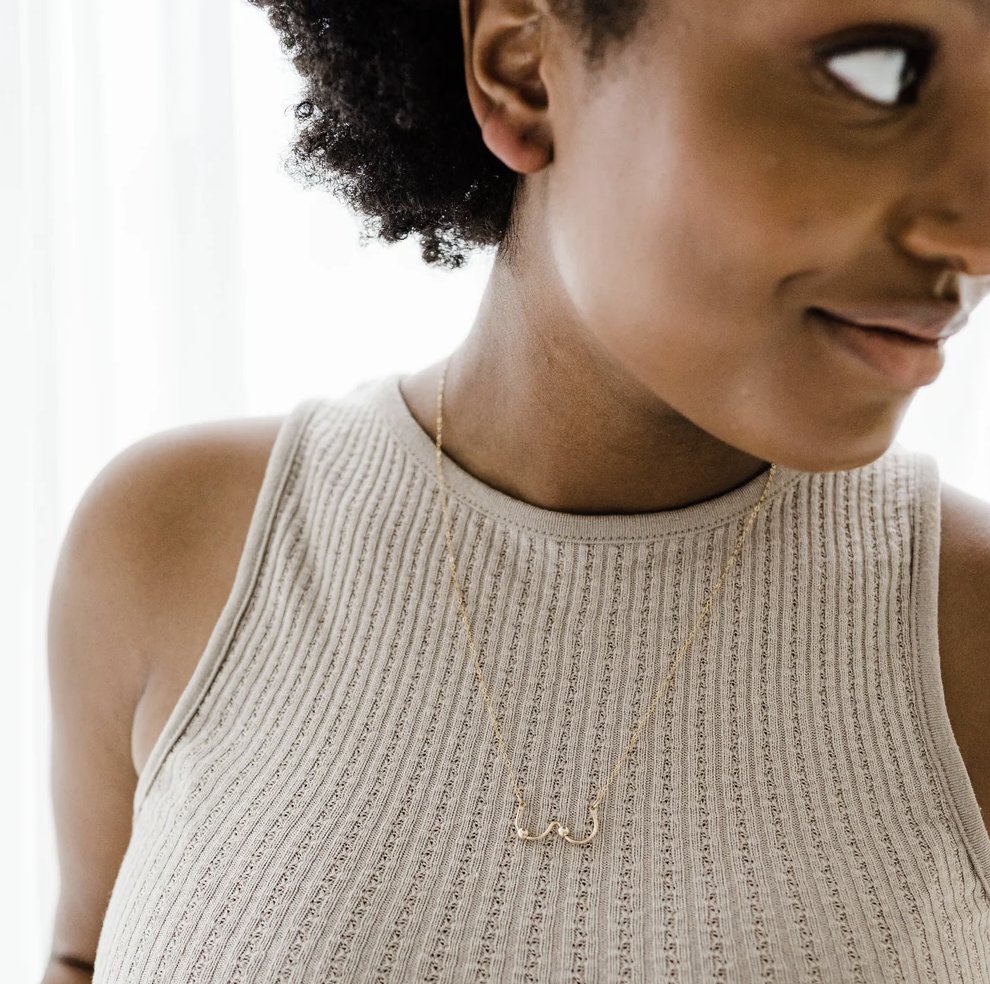 Hand formed "boobs" are adorned with 2 "nipples" in the same metal as the shaped wire. Attached to 20" of chain. Necklace is worn by a model and the necklace falls a few inches below the neckline.