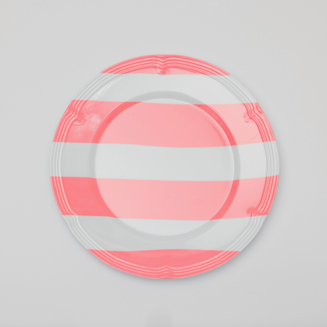 A melamine plate with pink and white stripes. 
