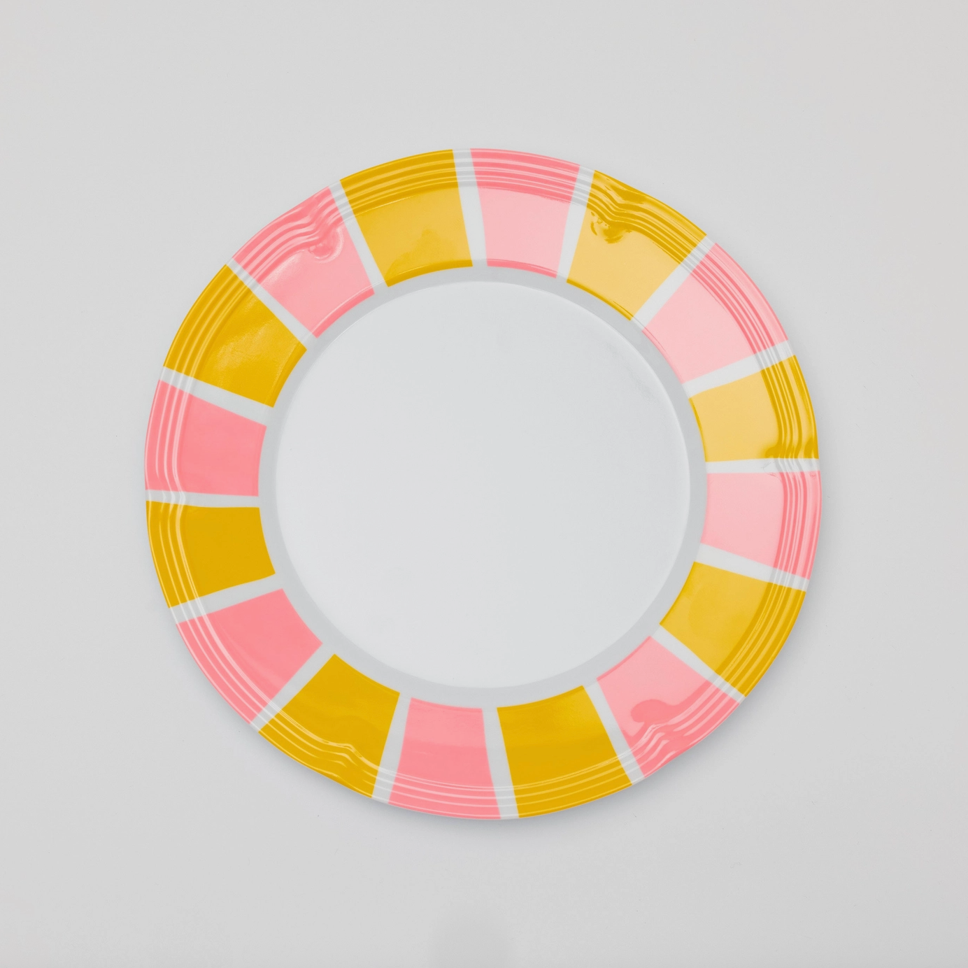 Pink and yellow stripes around the border of a white melamine plate. 