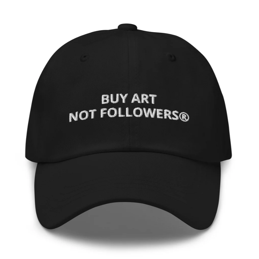 black dad cap with white embroidered text that reads buy art not followers.