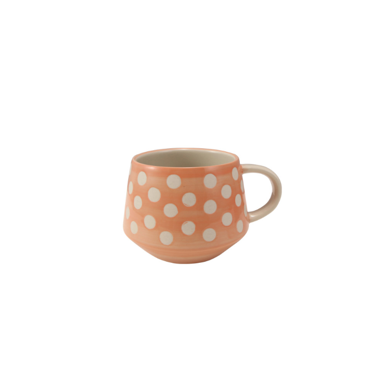 Ceramic mug with white polka dots on a peach background