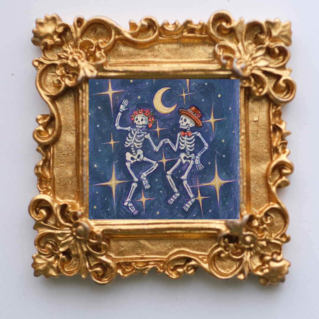 2 skeletons dance against stars and a dark sky. Inside a tiny gold ornate frame. 
