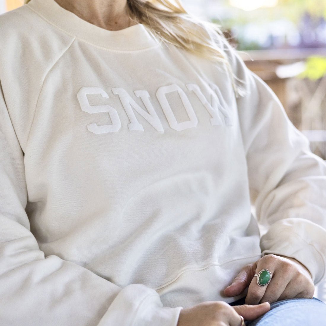 cream crewneck with "SNOW" in white font