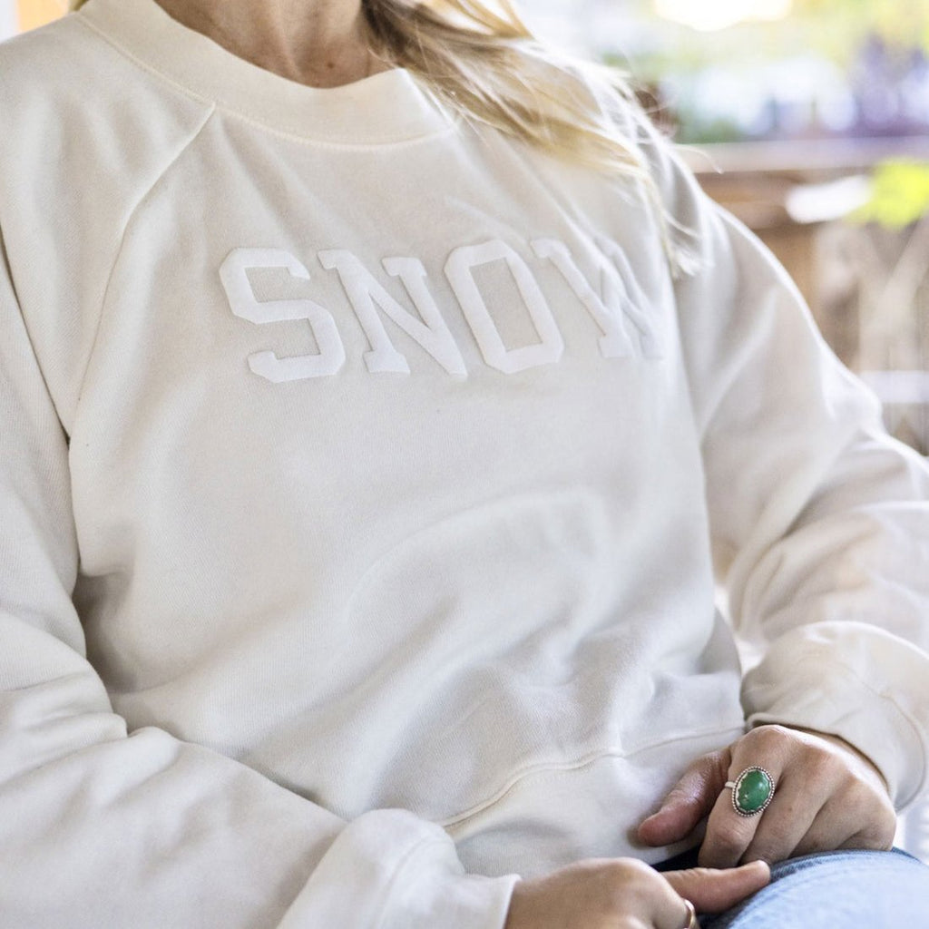 cream crewneck with "SNOW" in white font