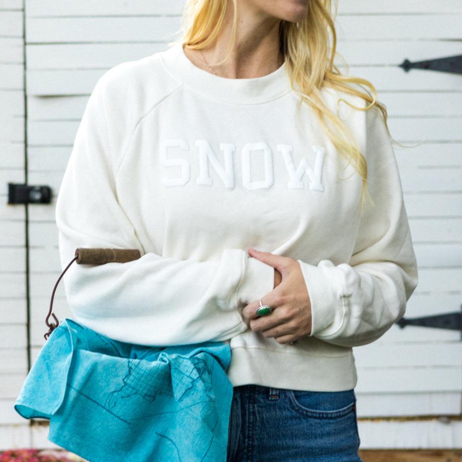 cream crewneck with "SNOW" in white lettering