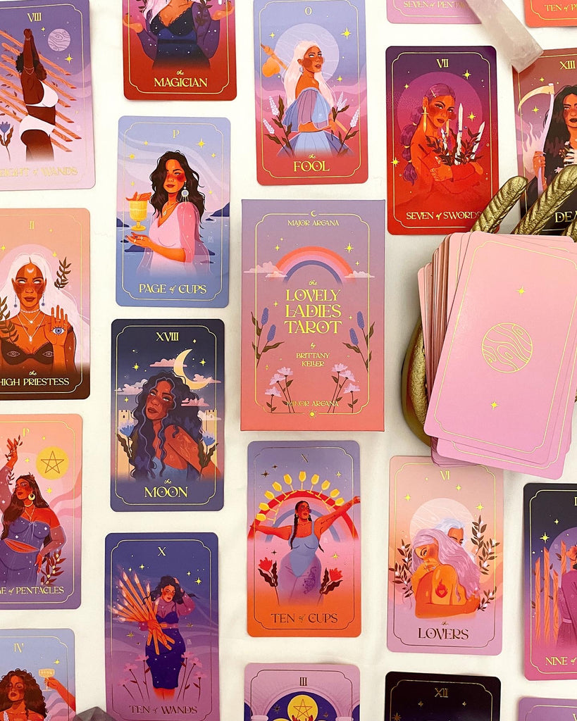 The Lovely Ladies Tarot Deck by Brittany Keller features stunning gold foiled cards depicting a woman-only major and minor arcana. Includes gold foiled box, beginner-friendly guidebook, and gold foiled cards with gold sprayed edges. The woman are colorful and powerful. 