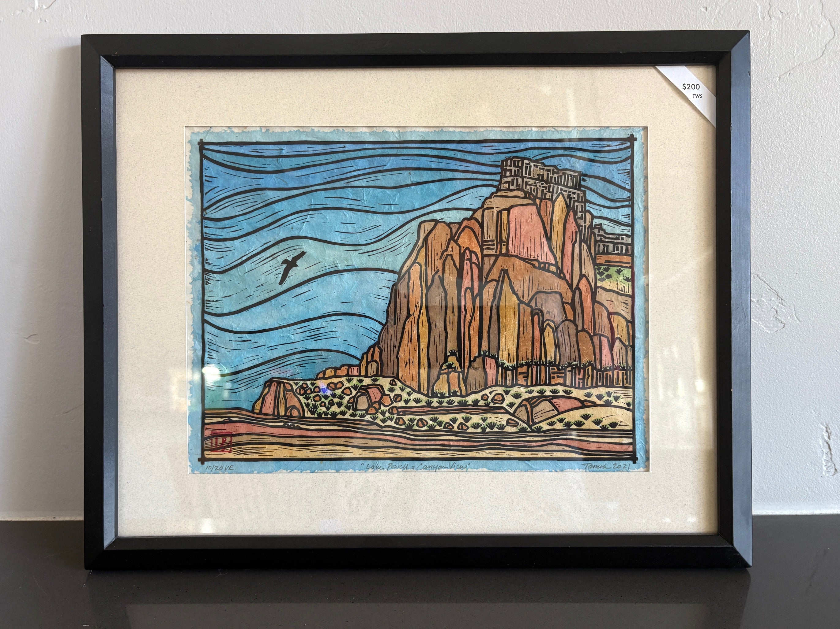 A view of the canyon in Lake Powell from the perspective of the water. An eagle is flying by and the sky is blue. 
