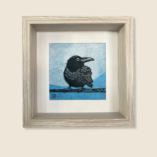 linocut on mulberry paper, image of a black raven, smiling to the side, with a blue sky background, the size is 6.75 x 6.75