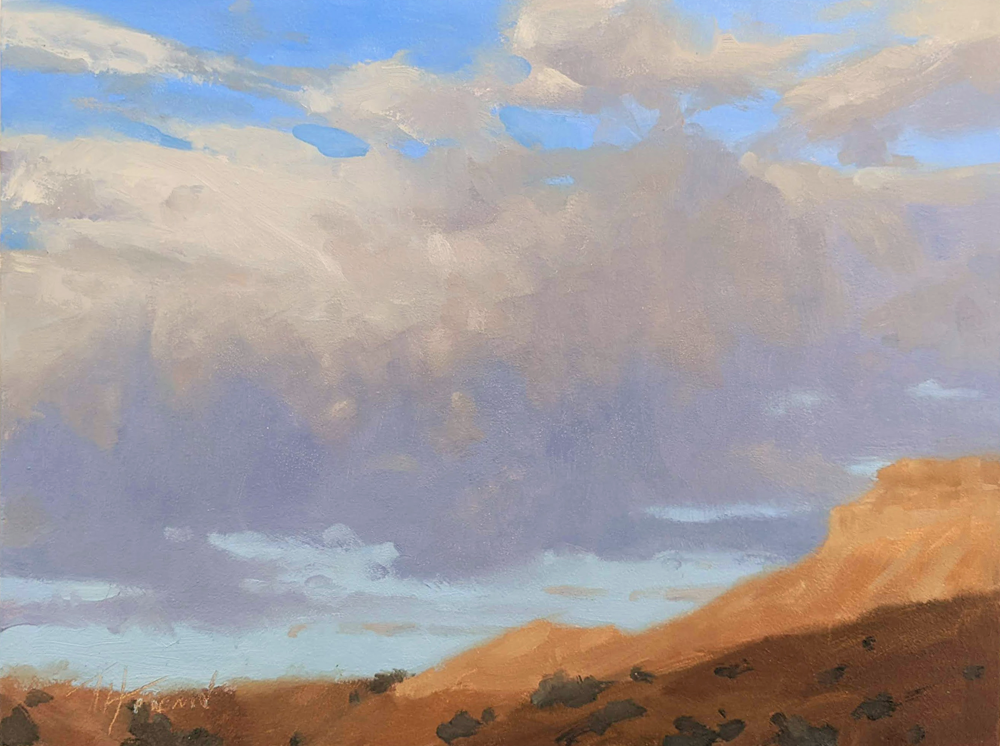 A dusky, cloudy sky over a red and brown desert landscape. Shadows are creeping up the hills. 