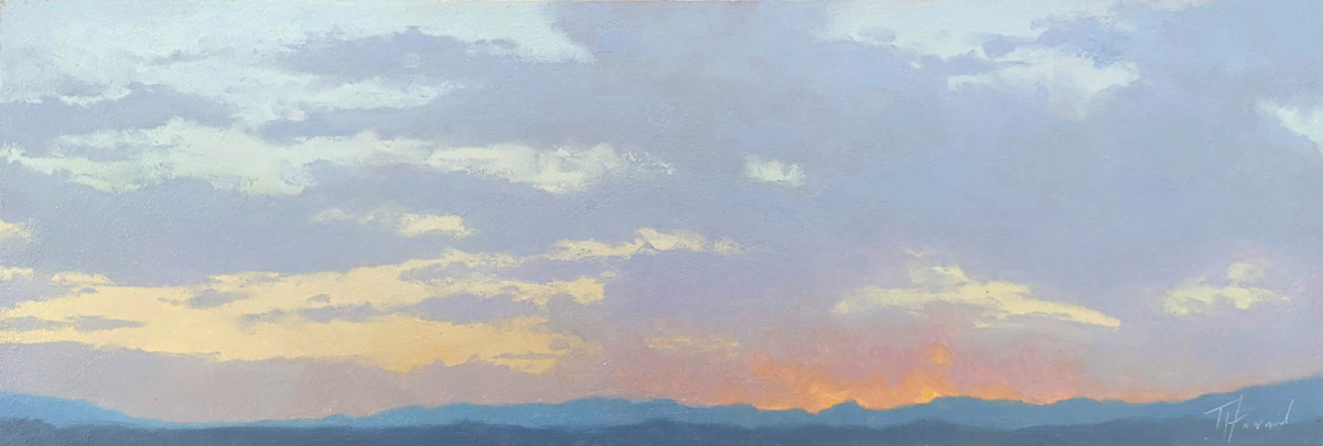 A dusky, purple and orange sky atop a blue mountain range. 