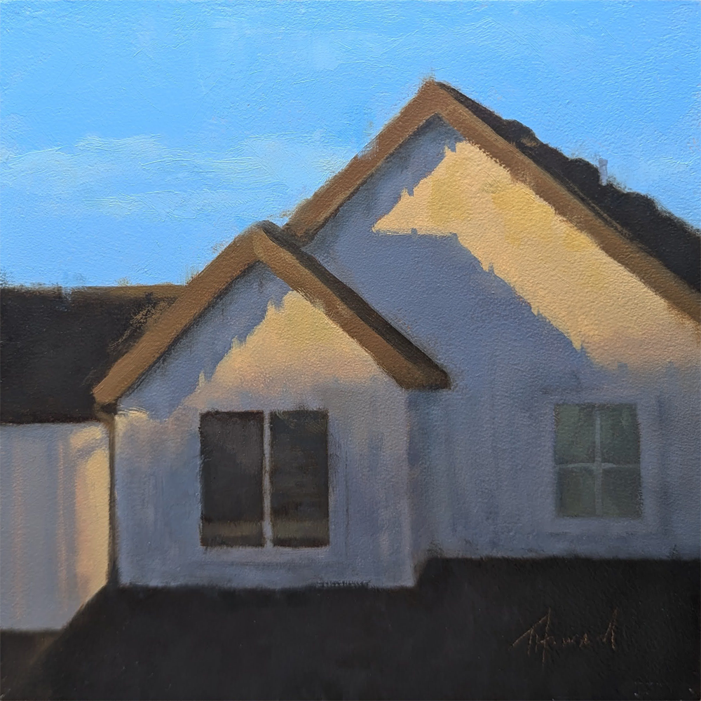 A close-up of a home with two rooms on the second floor. You can see two windows, one with two panes and one with four panes. The sky is blue behind it but the house is shadowed and reflecting an orange hue in the bask of dusk. 