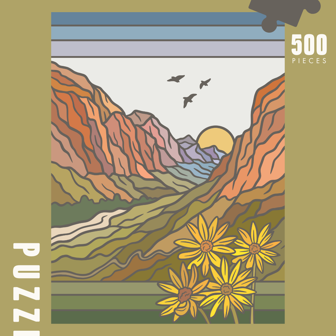 Image of puzzle box, showing full design of puzzle. Canyon walls in shades of orange with a green valley and sunset in the distance. 