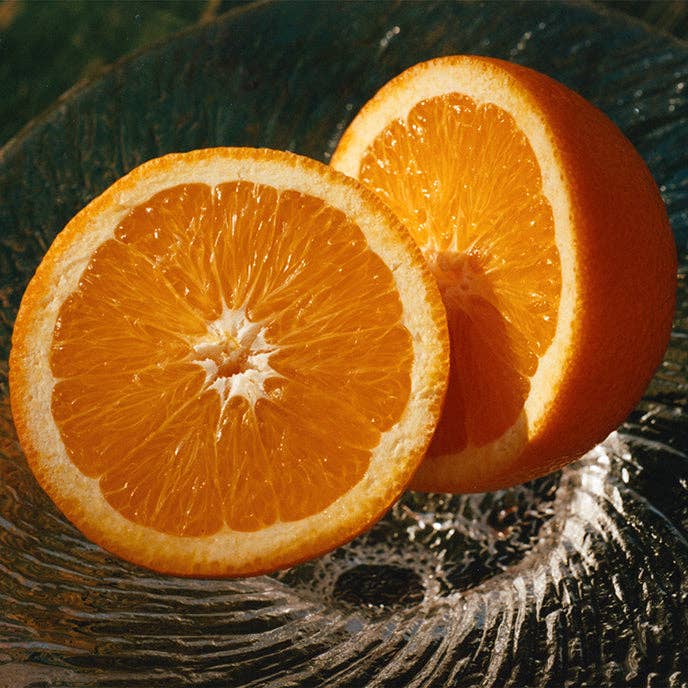 Two halves of an orange on a textured surface