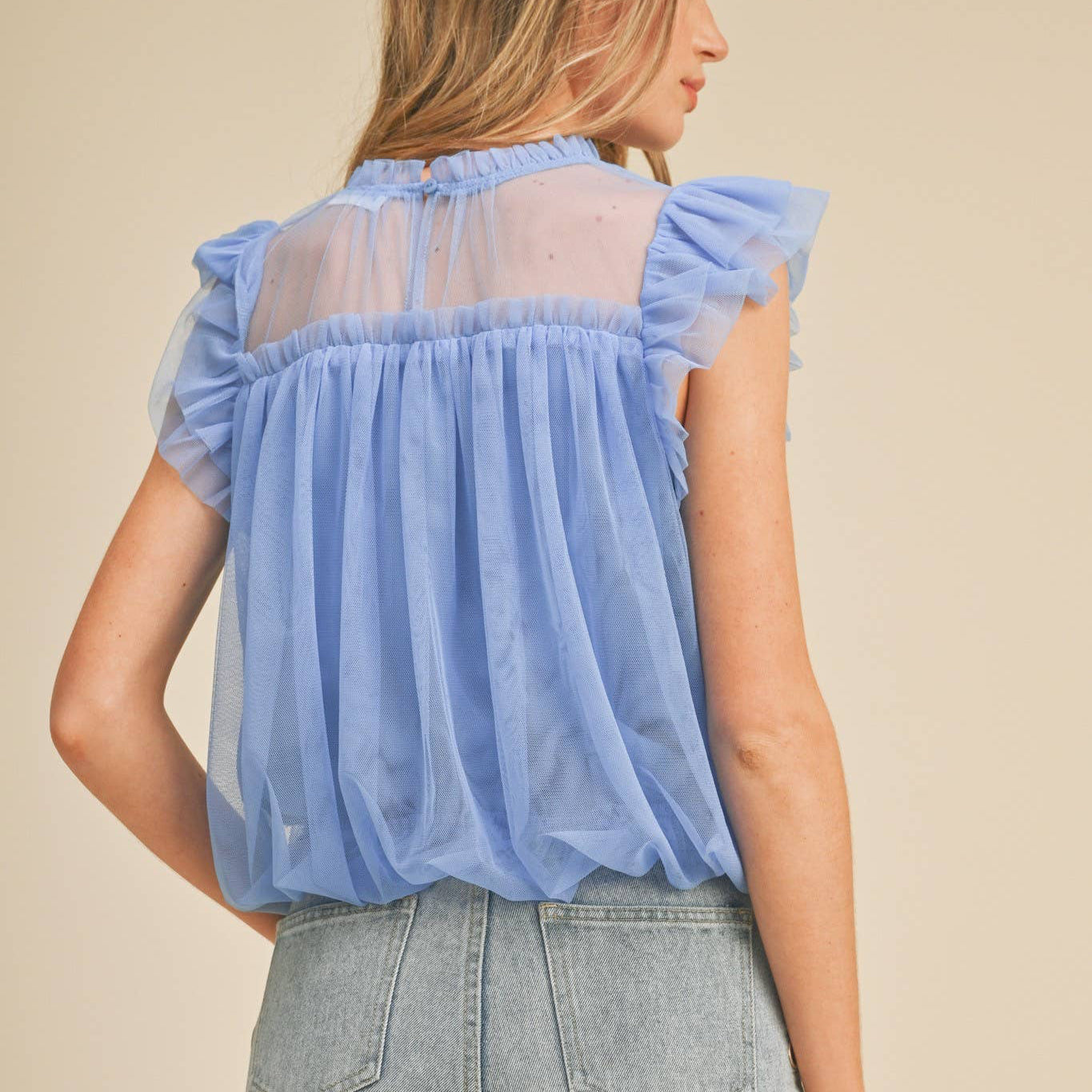 Embrace your softer side in this charming mesh ruffled flutter sleeve top. The delicate high ruffled neckline and playful flutter sleeves create an effortlessly romantic silhouette that celebrates your femininity. A bubble hem adds gentle movement and dimension, while the keyhole back with button closure offers a sweet surprise detail. Fully lined for comfort and confidence. Perfect for anyone seeking a piece that feels as good as it looks—a wardrobe staple that reminds you to be kind to yourself.